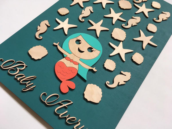 The baby shower guest book is made with a mermaid and sea horses, starfish and shells to be signed by your guests