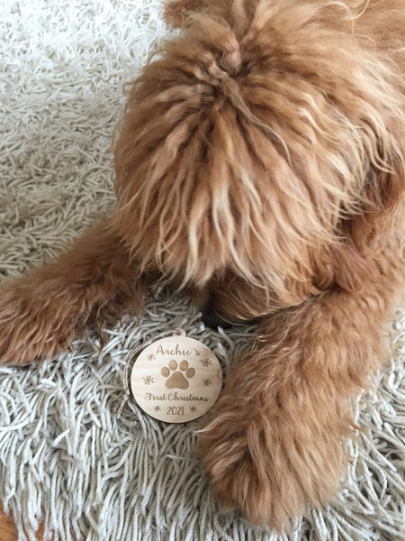 a fluffy doodle puppy showing off a personalized ornament with his name