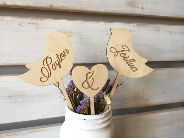 detail of Wooden wedding cake topper with love birds and heart engraved with personalized couple's name