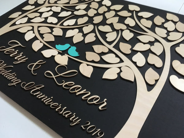 detail of wedding anniversary guest book with two trees growing as one and love birds