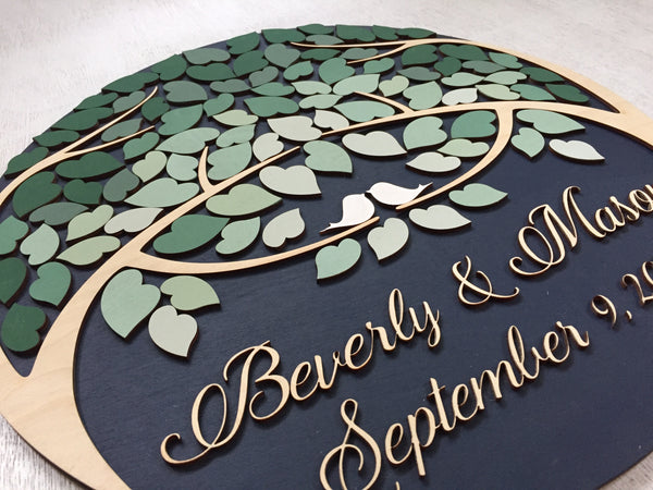 left side detail of custom guest book round sign with trees and dark green ombre leaves to sign