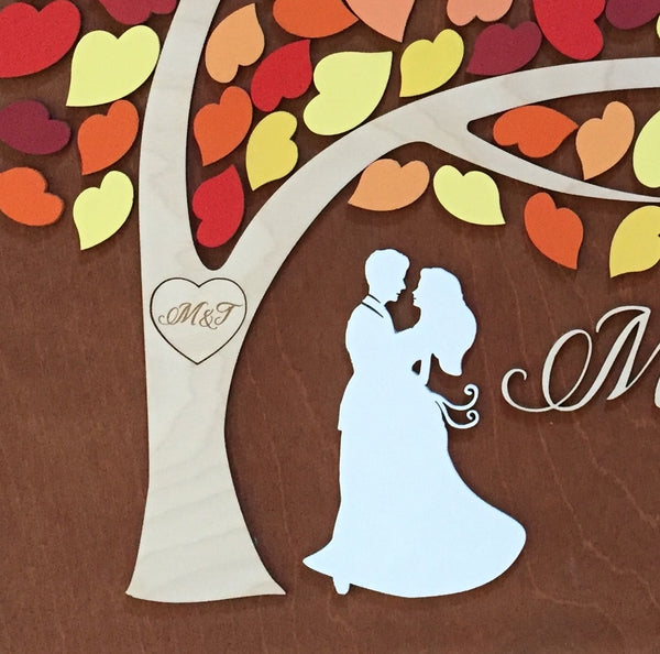 Detail of the guest book alternative tree showing the heart and engraved initials and the silhouette of the couple, all made with personalized details and colors.