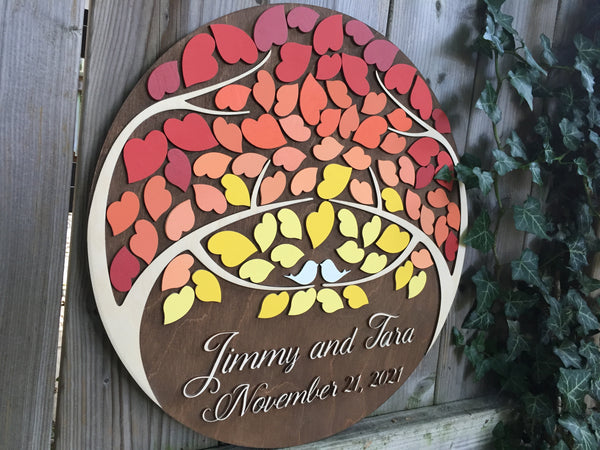 the round guest book is made with two trees coming together and leaves to sign made by sign you style